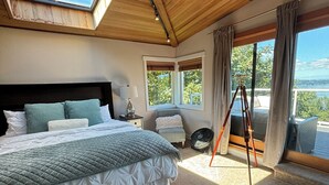 Ein Schlafzimmer mit einem großen Bett, einem Dachfenster und Blick ins Freie.