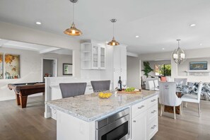 A modern kitchen with a central island, white cabinetry, and pendant lighting. - Valley Views: Newly Remodeled 4br 4ba with Spectacular Valley Views (Carmel)