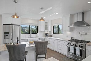 A modern kitchen with a central island, stainless steel appliances, and large windows offering views of the outdoors. - Valley Views: Newly Remodeled 4br 4ba with Spectacular Valley Views (Carmel)