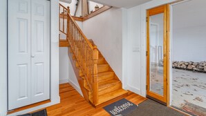 A staircase with wooden steps and a wooden handrail, leading to a room with a white door and a glass door.