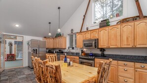 A modern kitchen with wooden cabinets, a central island, and stainless steel appliances.