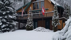 A wooden cabin with a balcony, surrounded by snow-covered trees.