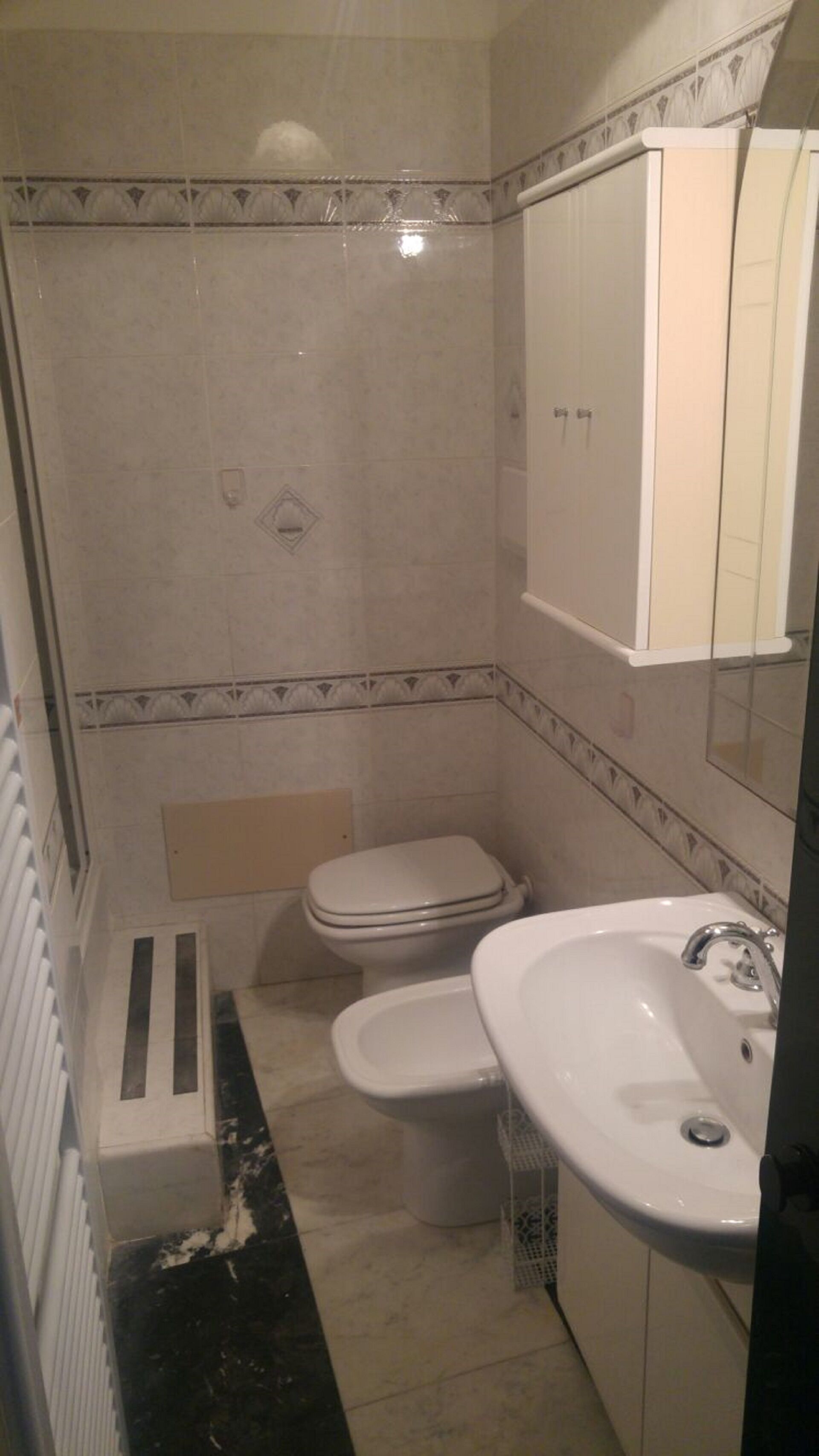 A small bathroom with a toilet, sink, and shower.