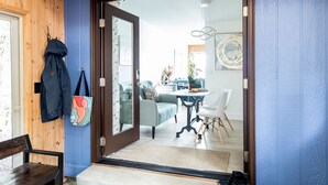 A wooden interior with a blue wall, a wooden ceiling, a door leading to a dining area, and a bench with a bag hanging on it. - Stunning Waterfront - PNW Gem,  Hot Tub, Mountain Views, Fireplace (Olympia)