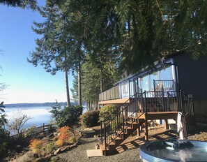Une cabane dotée d’une terrasse et d’un escalier menant à un balcon offrant une vue sur un lac.