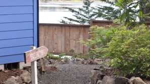 A wooden signpost with the word "BEACH" pointing towards a gravel path leading to a wooden fence overlooking a lake. - Stunning Waterfront - PNW Gem,  Hot Tub, Mountain Views, Fireplace (Olympia)