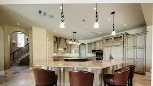 A spacious kitchen with a central island, bar stools, and pendant lighting. - Waterfront Paradise in Marco Island (Marco Island)