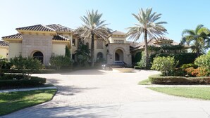 A large, multi-story building with a tiled roof, palm trees, and a paved driveway. - Waterfront Paradise in Marco Island (Marco Island)