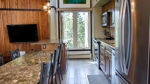 A modern kitchen with a granite countertop, stainless steel appliances, and a dining area with wooden chairs. - 2 BR Updated Condo-Mountain View! Excellent location, views & value! (Breckenridge)