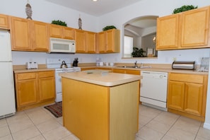 Fully equipped kitchen with central island, microwave, toaster, kettle, and dishwasher.