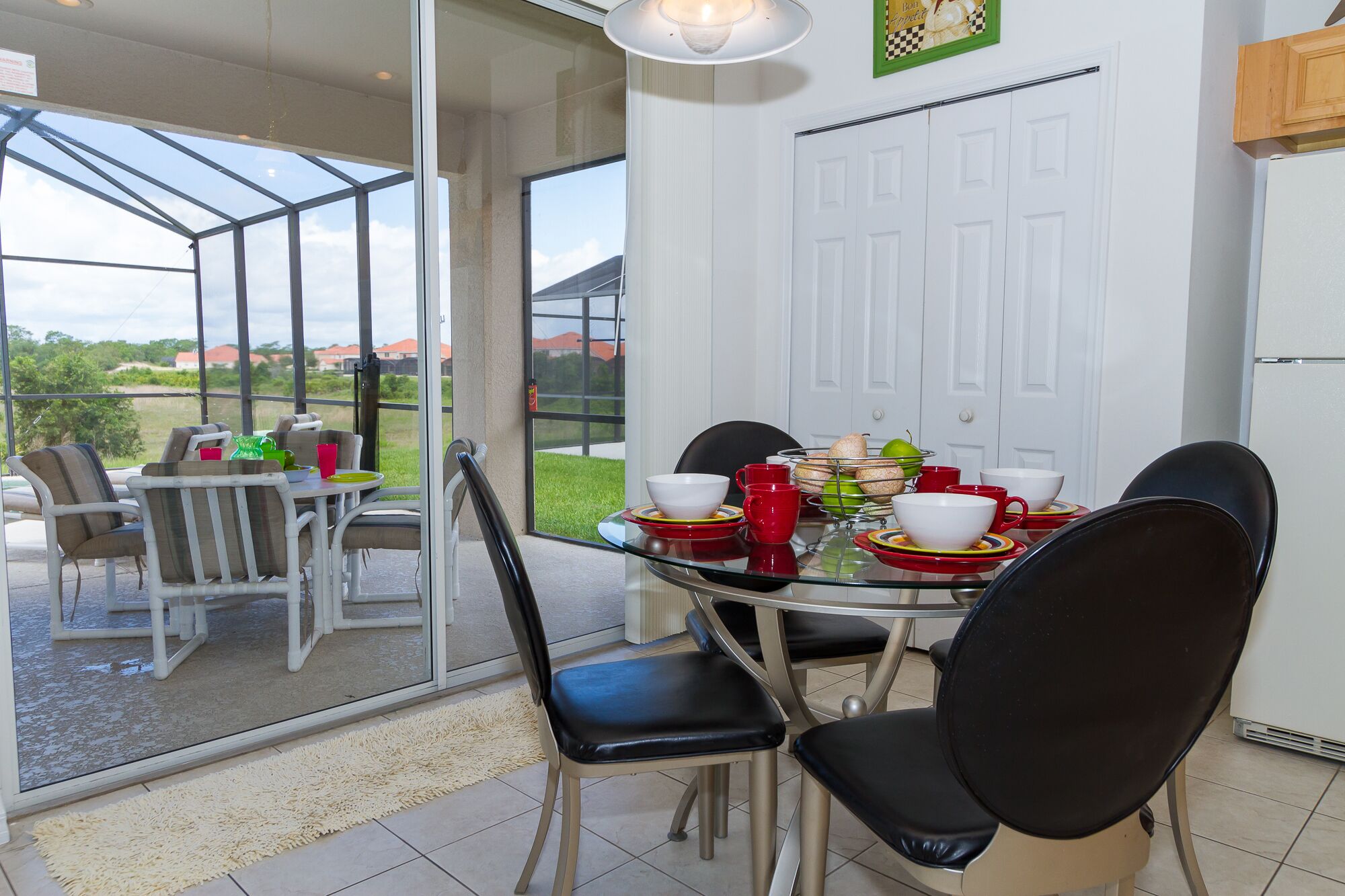 Un espace repas avec une table en verre, des chaises et une vue sur l’extérieur.