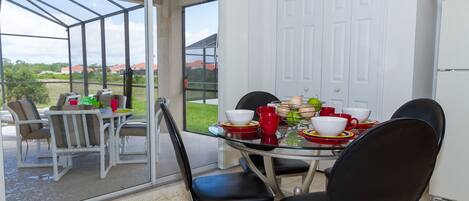 Un espace repas avec une table en verre, des chaises et une vue sur l’extérieur.
