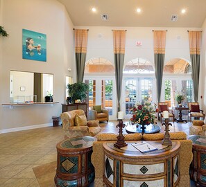 A spacious lobby with high ceilings, large windows, and a central seating area with a coffee table.