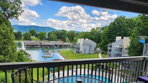 A balcony with a view of a lake, docked boats, and a building with a flat roof.