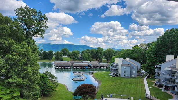 A resort with a swimming pool, docked boats, and a view of mountains.