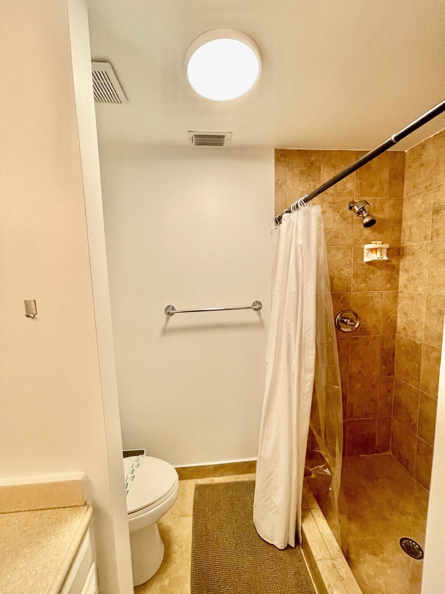 Un baño con ducha, inodoro y perchero para toallas.