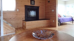 Un intérieur en bois avec une cheminée, un lit et un escalier.
