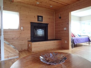 A wooden interior with a fireplace, a bed, and a staircase. - Cozy Vacation Cottage on All Sports Lake Chemung ~ Includes Kayaks!   (Howell)