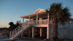 A beachfront house with a balcony, a staircase, and a palm tree. - Beach Front South End, Designer Decorated, Dream Retreat on Tybee Island! (Tybee Island)