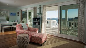 A spacious living room with a large sliding glass door leading to a balcony with a view of the sea. - Beach Front South End, Designer Decorated, Dream Retreat on Tybee Island! (Tybee Island)