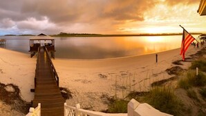 A wooden pier leading to a covered structure by a calm lake at sunset. - Beach Front South End, Designer Decorated, Dream Retreat on Tybee Island! (Tybee Island)