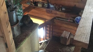 Puinen portaikko, jonka sisustuksessa on maalaishenkinen tyyli. Portaikossa on hylly, jossa on erilaisia esineitä, sekä ruukussa oleva kasvi.