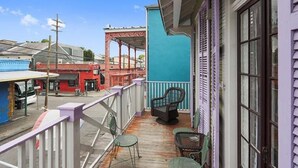 Un balcon donnant sur une rue, un immeuble rouge et un mur bleu.