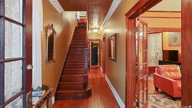 Un magnifique escalier menant à un deuxième étage, flanqué de portes en bois et bordé d’œuvres d’art encadrées.