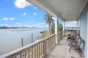 A wooden deck with outdoor furniture overlooking a marina with boats and a clear sky. - 3BR Bayfront Cottage | Sleeps 6 | Deck & Wildlife Views (Gulf Shores)
