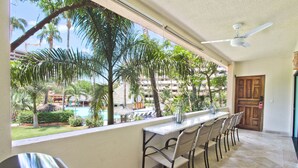 Ein Balkon mit Blick auf einen Pool, Palmen und ein Gebäude im Hintergrund.