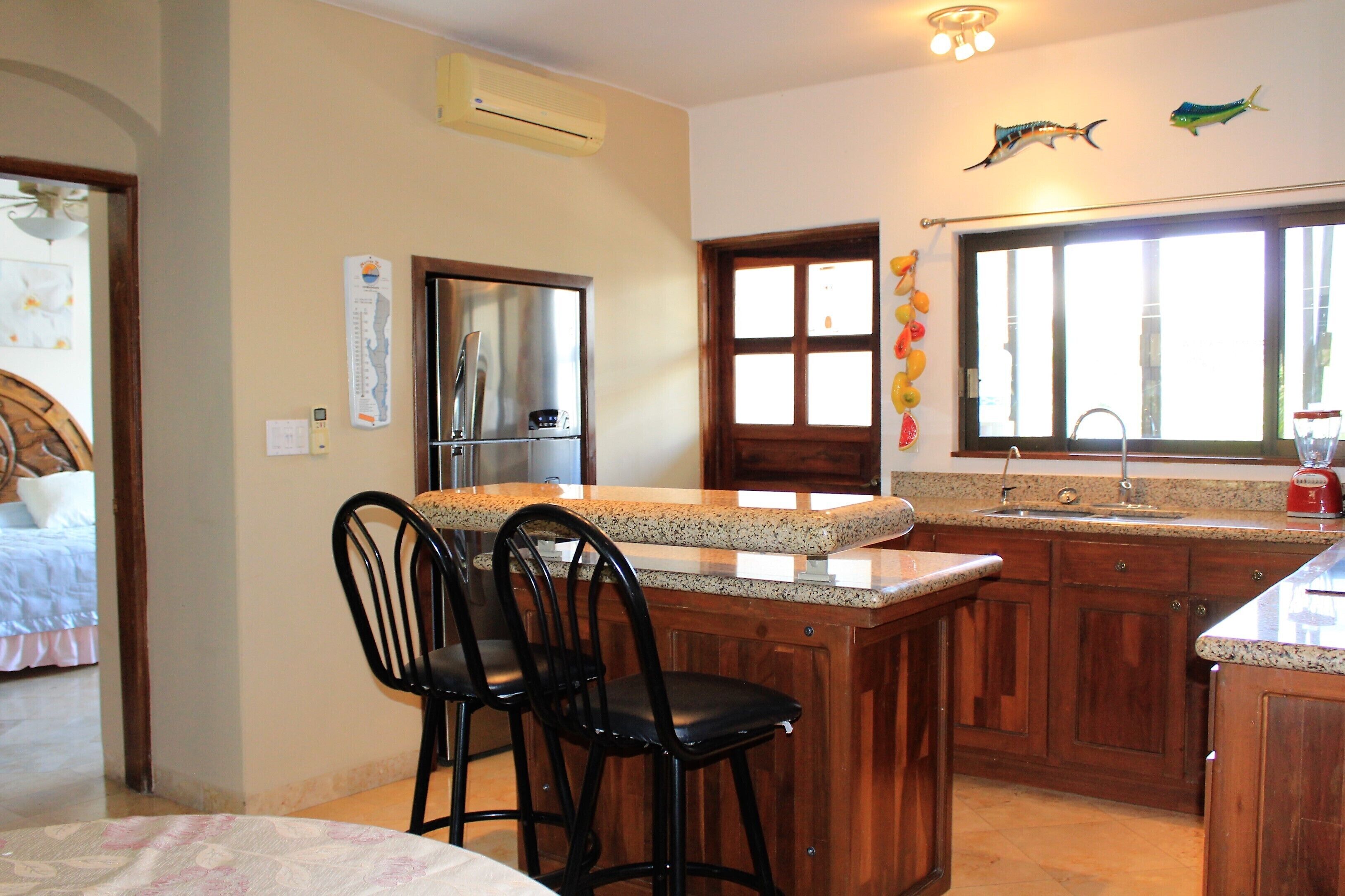 A kitchen with wooden cabinets, a granite countertop, and a stainless steel refrigerator.