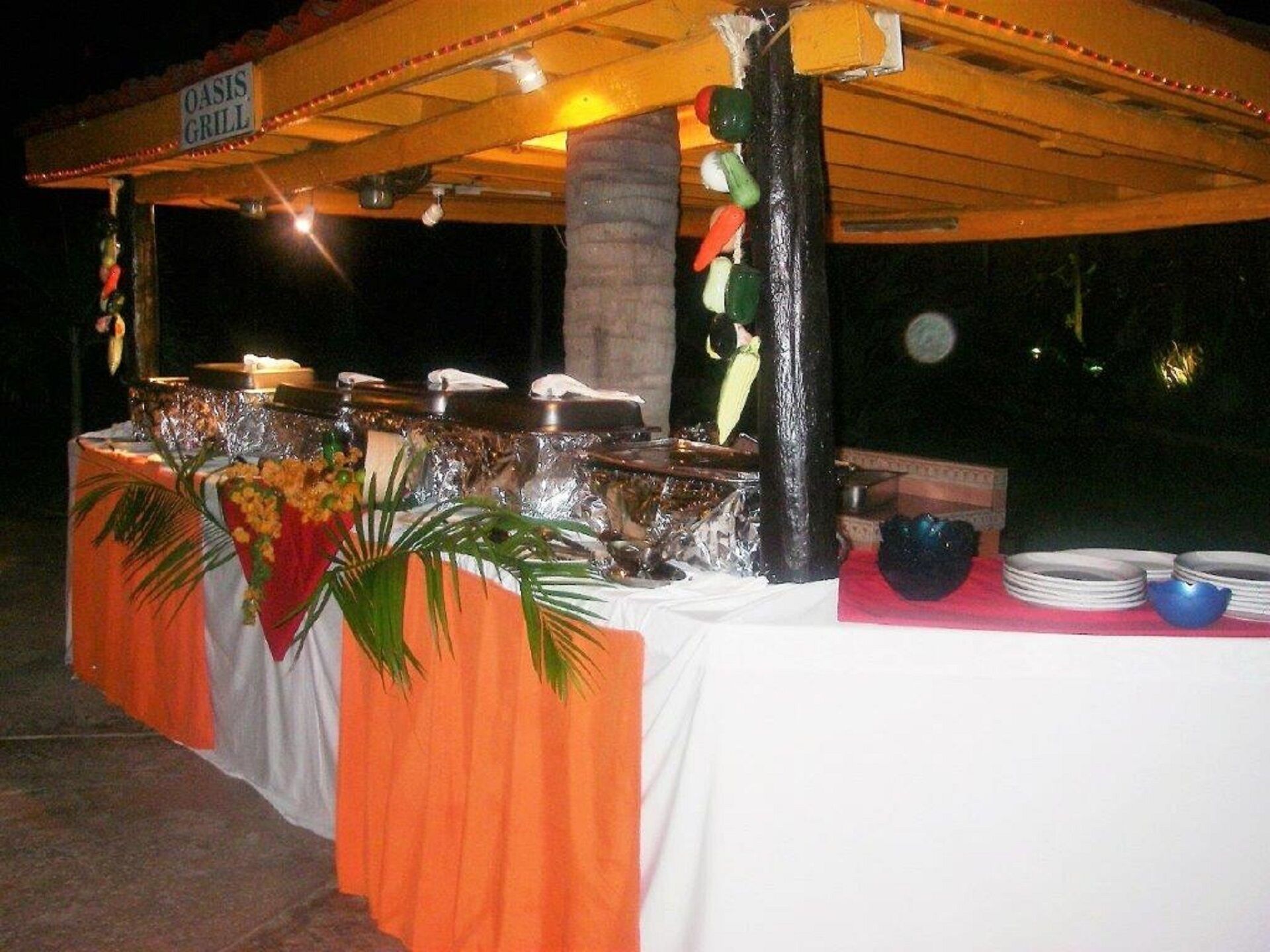 Een buffet met een bordje waarop 'OASIS GRILL' staat en diverse gerechten.