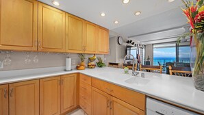 Cocina con armarios de madera, encimera blanca y lavavajillas.