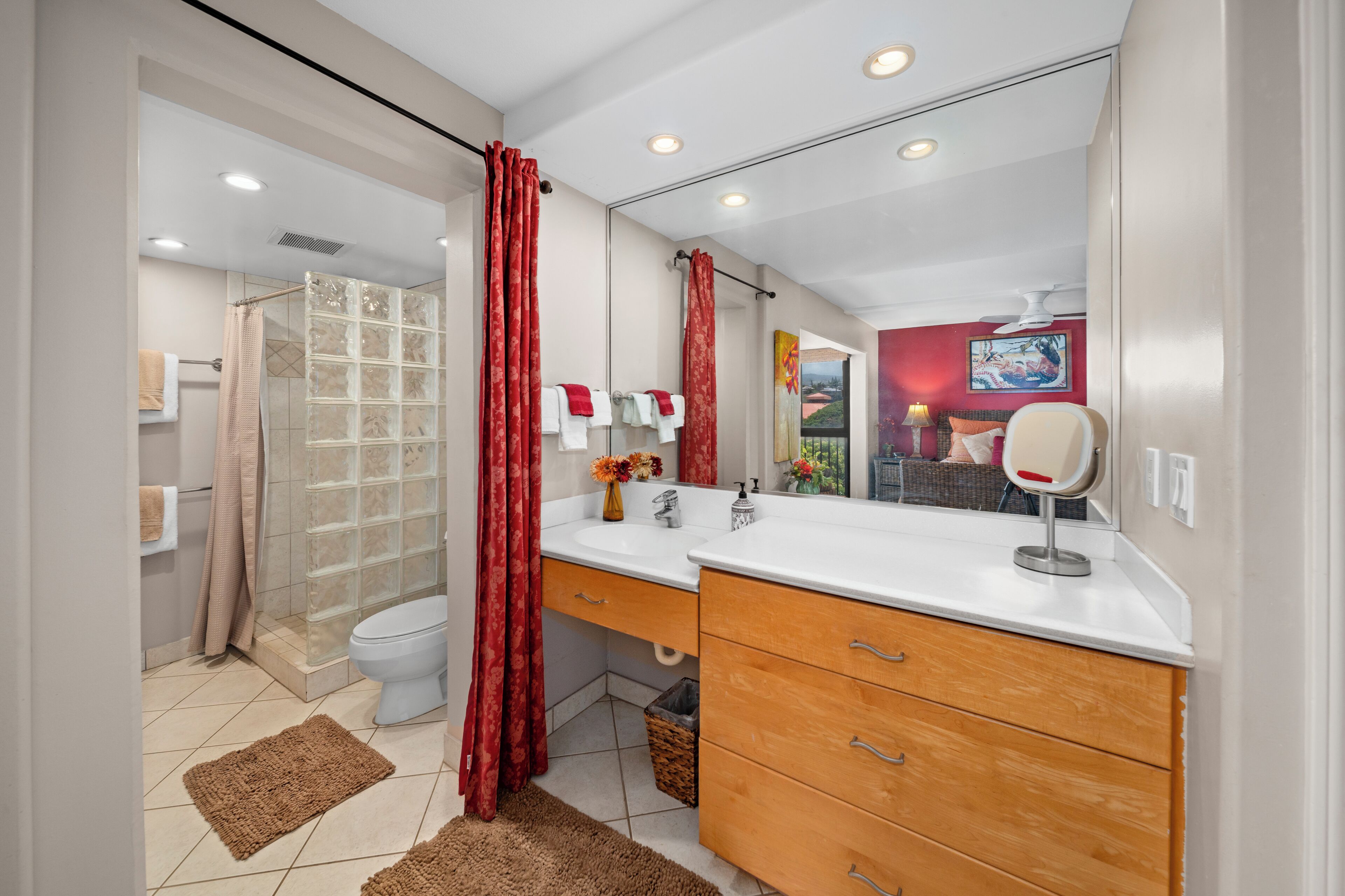 A modern bathroom with a glass shower enclosure, a white toilet, and a vanity with a mirror.