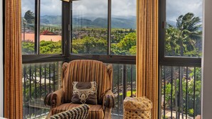 Habitación de esquina con ventanas amplias que ofrecen vistas a un paisaje exuberante y montañas.