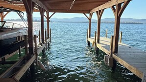 A wooden pier extending into a body of water with a clear view of the water and distant hills.
