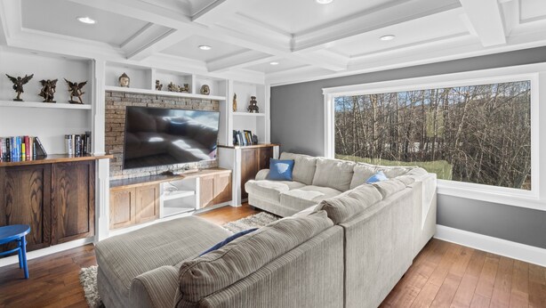 Un salon moderne doté d’un grand téléviseur à écran plat, d’un canapé d’angle, de meubles en bois et d’une cheminée.