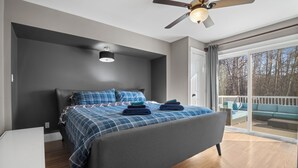 Une chambre à coucher avec un lit, un ventilateur de plafond, une fenêtre et une vue sur l’extérieur.