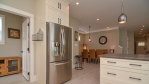 A modern kitchen with a stainless steel refrigerator, white cabinetry, and a dining area with a wooden table and chairs.