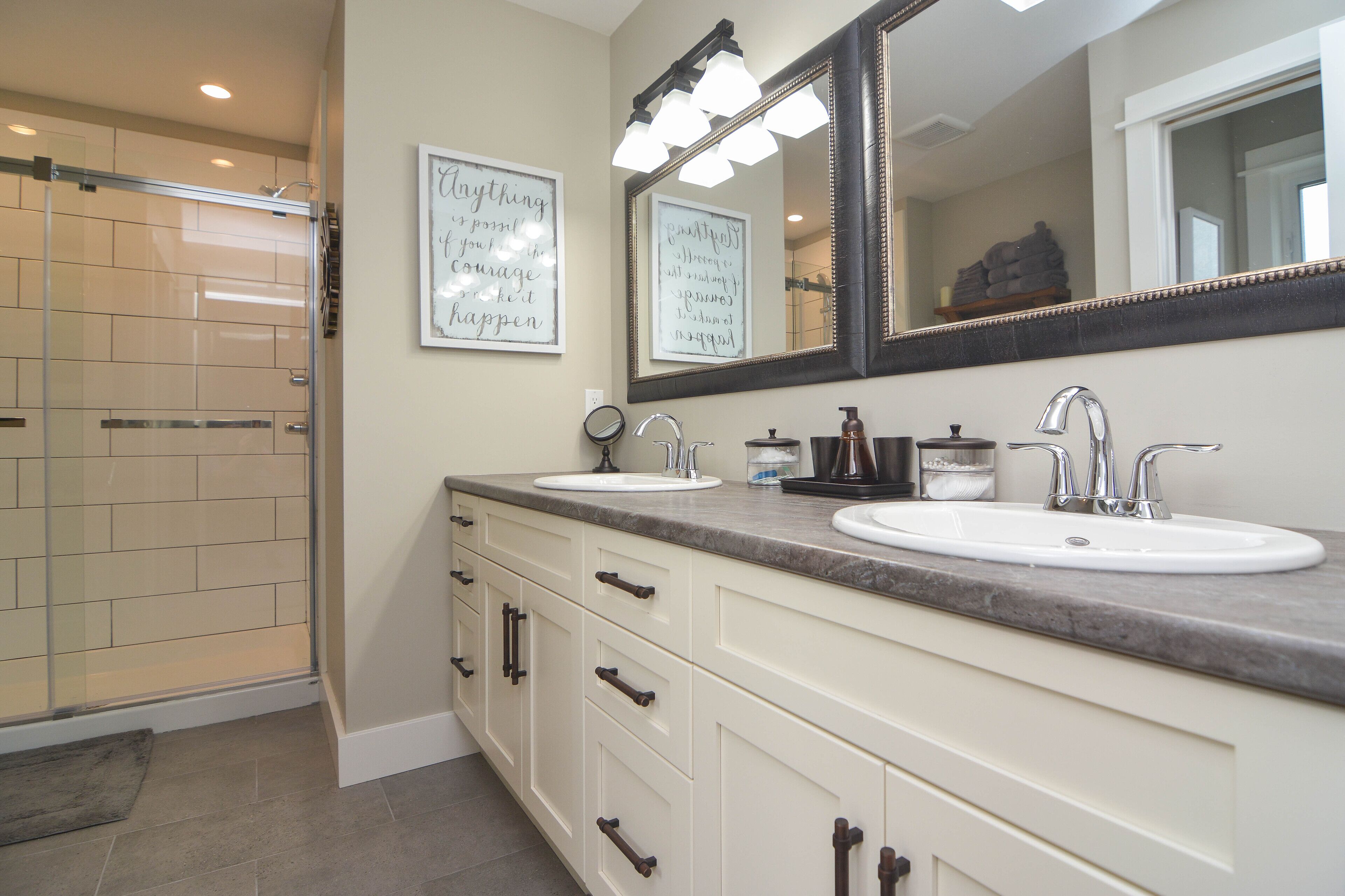 A bathroom with two sinks, a large mirror, and a shower area.