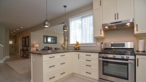 A kitchen with a central island, stainless steel appliances, and pendant lighting.