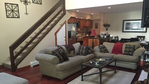 A living room with two sofas, a coffee table, a rug, and a staircase.