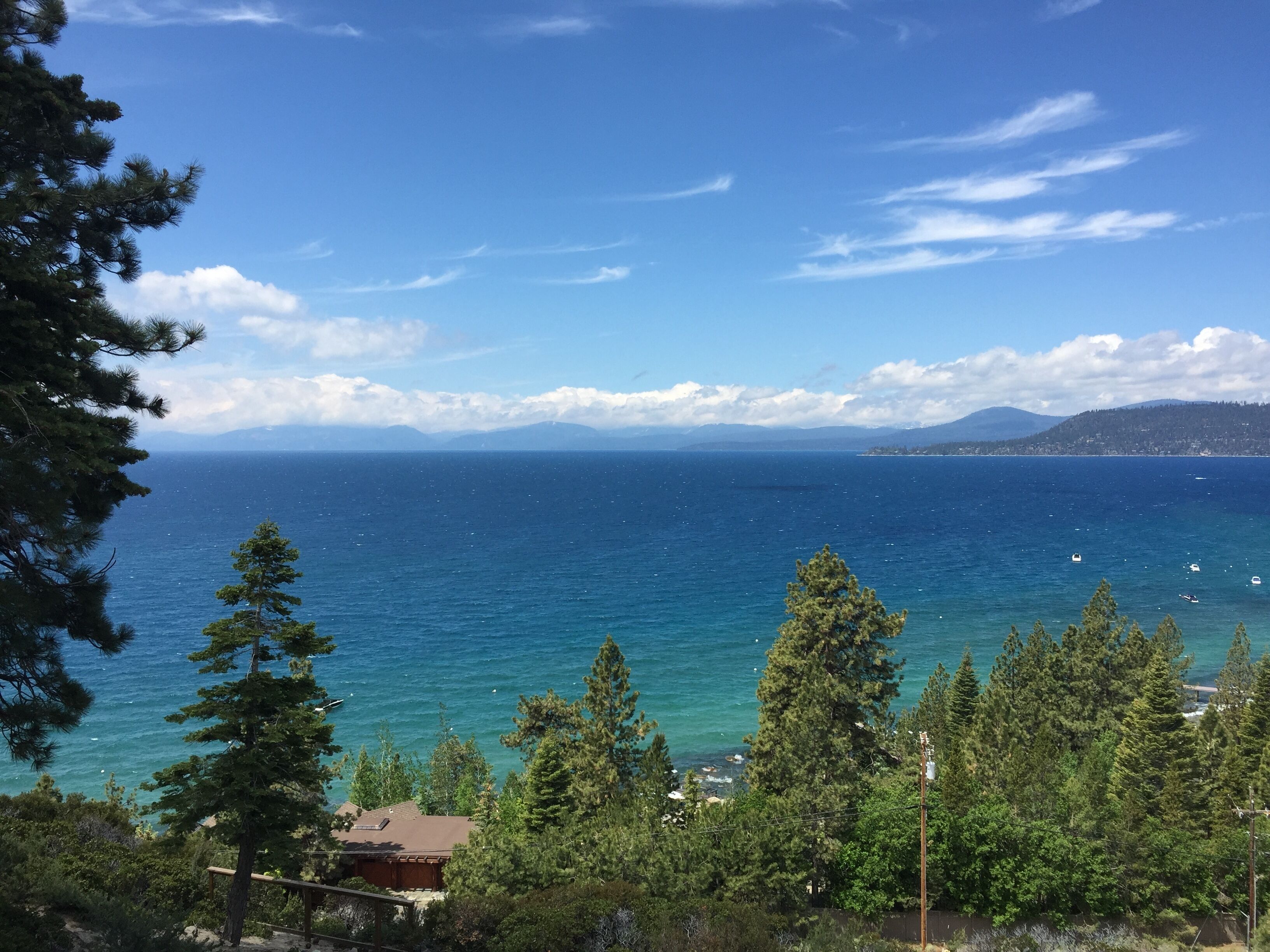 Vista sulla costa con cielo sereno, un corpo d'acqua e una catena montuosa in lontananza.