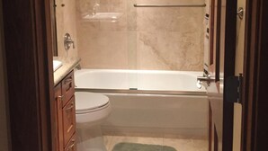 A bathroom with a bathtub, toilet, and vanity.