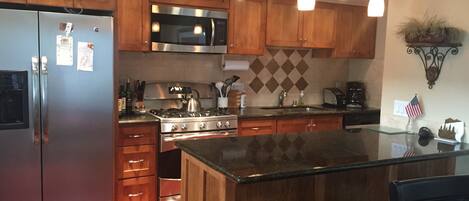 A modern kitchen with wooden cabinets, stainless steel appliances, and a central island with seating.