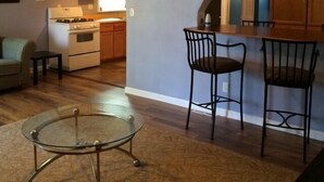 A compact kitchen with an archway leading to a dining area, a ceiling fan, and a clock on the wall. - Conesus Lake Cottage Rental (Conesus)