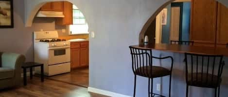 Una cocina compacta con un arco que da a un comedor, un ventilador de techo y un reloj en la pared.