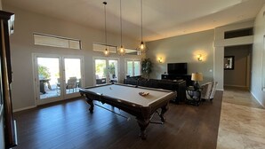 A spacious living room with a pool table, a television, and a seating area. - Desert Retreat - 4BR/3BA Heated Pool & Spa - Recently Renovated - Monthly Rental (Scottsdale)