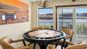 A round table with chairs, a chandelier, and a large painting of a concert scene. - 15 min to The Gorge! HotTub, Tesla/EV Charger, Cave B Estate Winery! (Vantage)