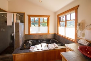 A bathroom with a large bathtub, a shower, and a window providing natural light. - Ocean View King Suite in Mendocino Village with Free Wi-Fi and Jacuzzi Bathtub (Mendocino)